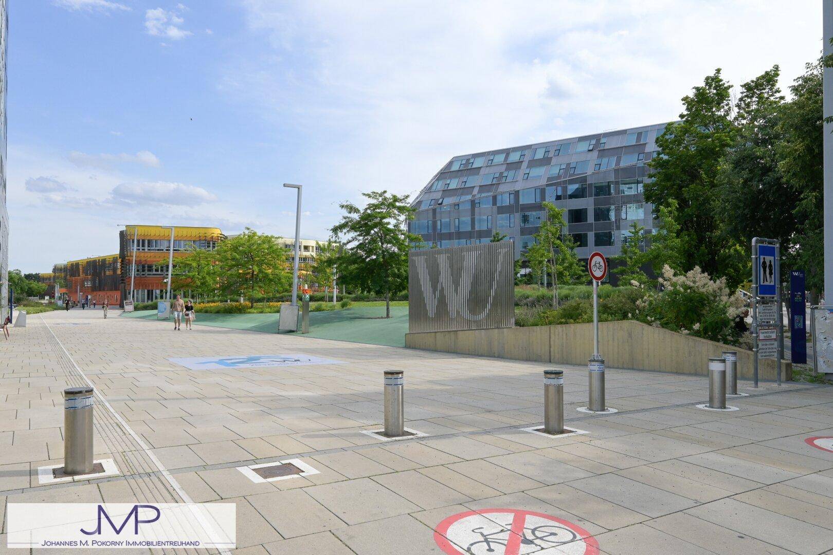 Moderner Universitäts-Campus mit zeitgenössischen Gebäuden und weitläufigen, gepflasterten Gehwegen.