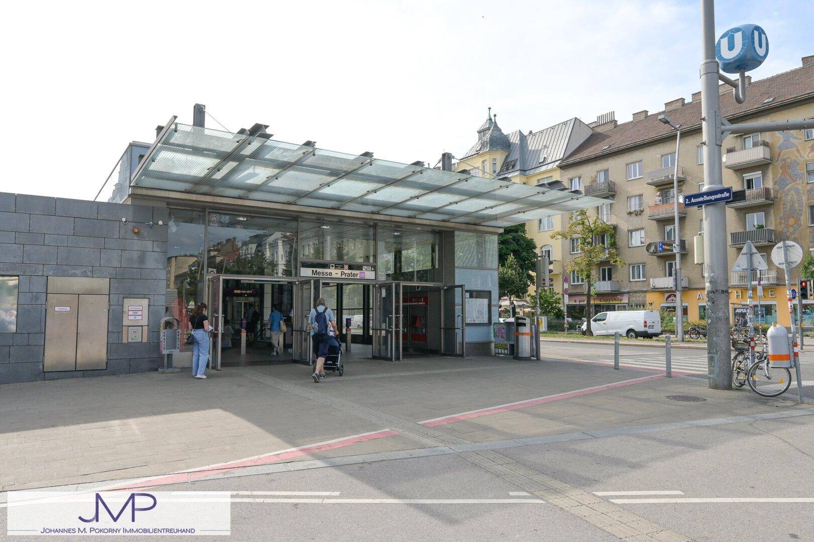 Eingangsbereich einer U-Bahn-Station mit Glasdach und Passanten, die den öffentlichen Nahverkehr nutzen.
