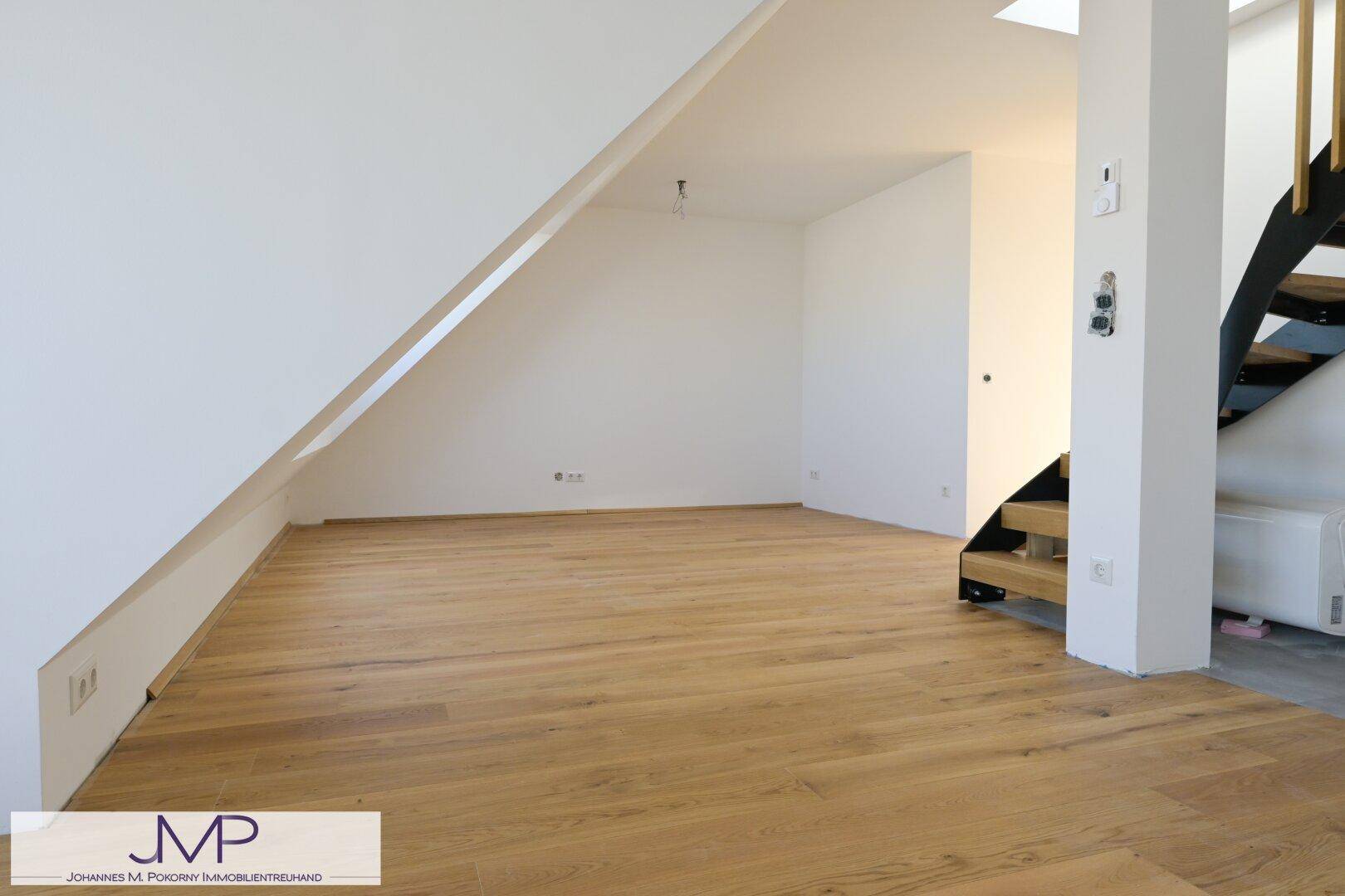 Unmöblierter Wohnraum mit Dachschräge und Holzboden, bietet viel Gestaltungspotenzial.