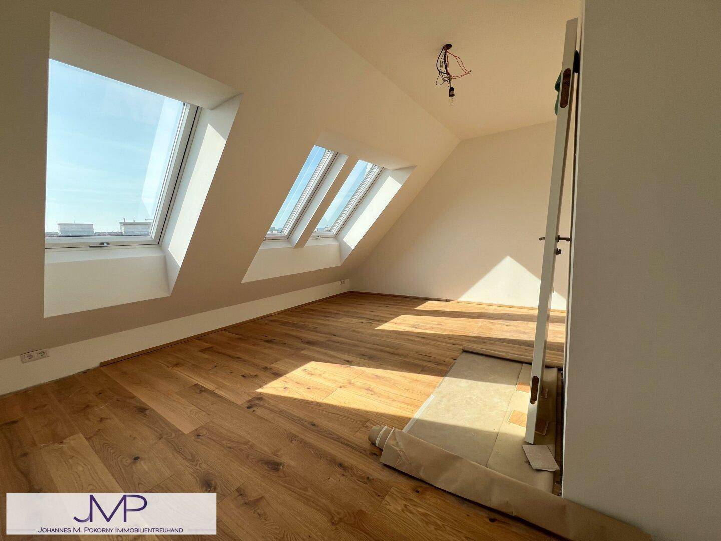 Schlafzimmer mit Holzboden, Dachschrägen und zwei großen Dachfenstern für viel Licht.