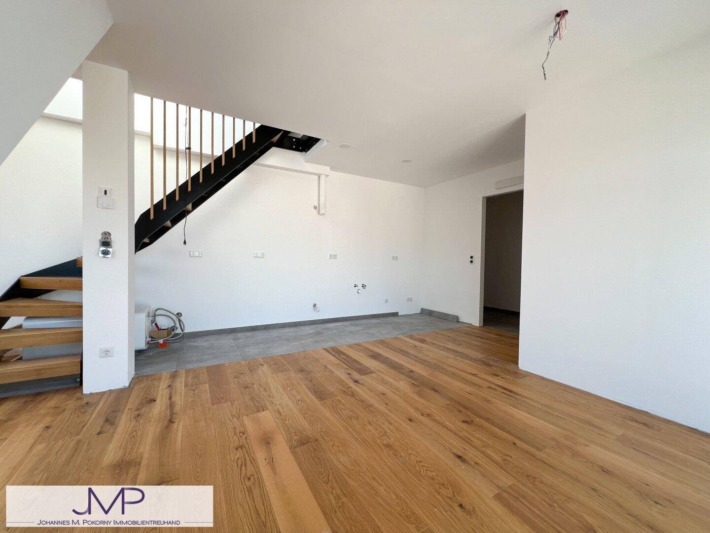 Geräumiger Wohnbereich mit Holzboden und Treppe, bereit für individuelle Gestaltung.