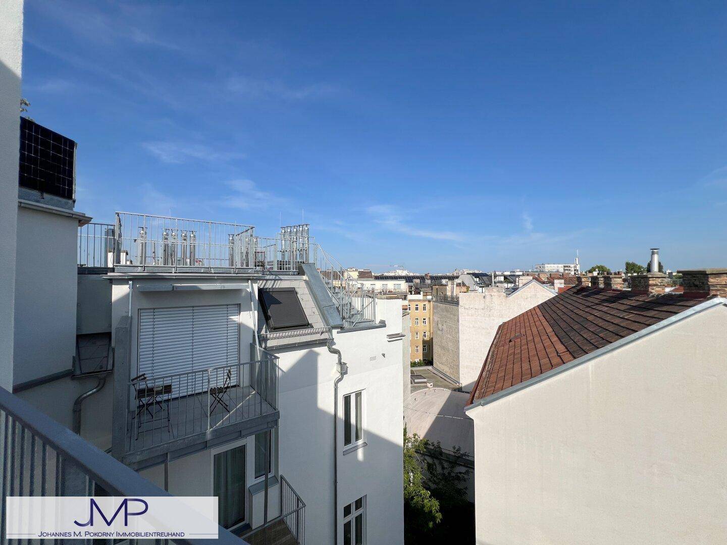 Balkon mit Blick auf die umliegenden Gebäude und den blauen Himmel.