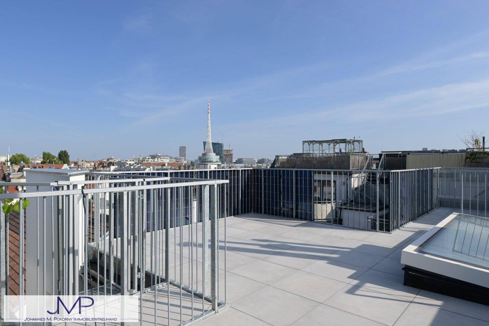 Große Dachterrasse mit Fliesenboden und weitem Blick über die Stadt.