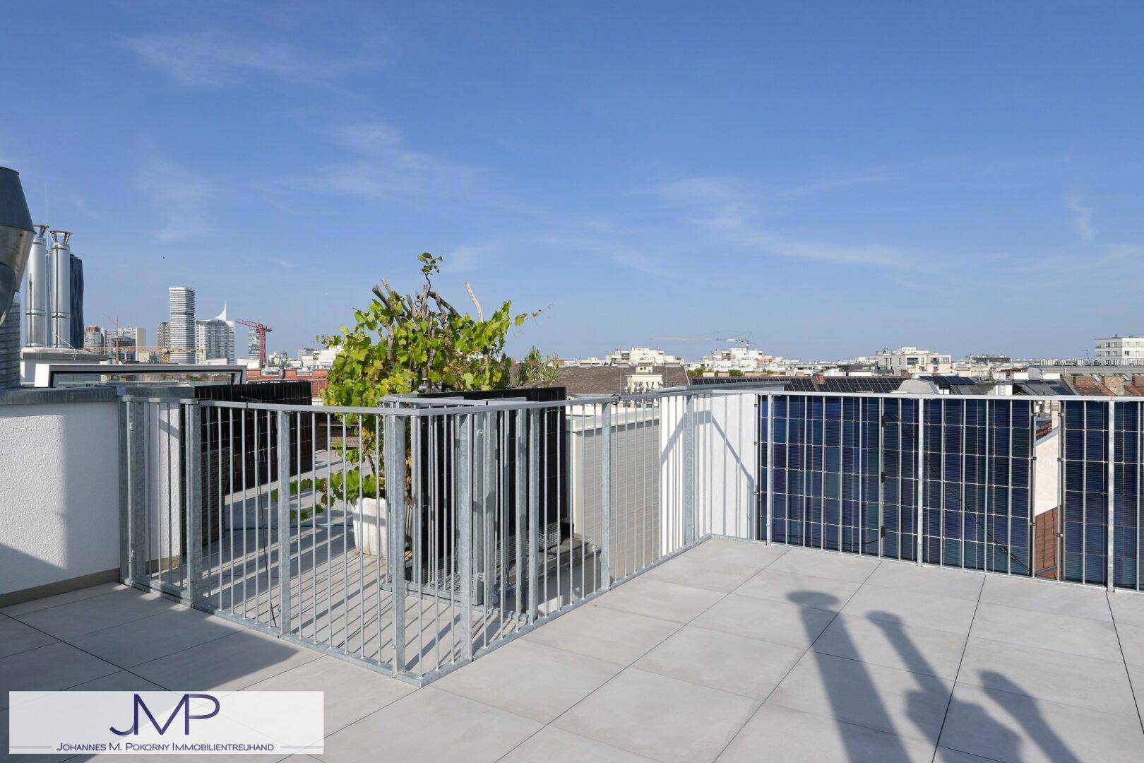 Geräumige Dachterrasse mit Fliesenboden und moderner Metallbrüstung.