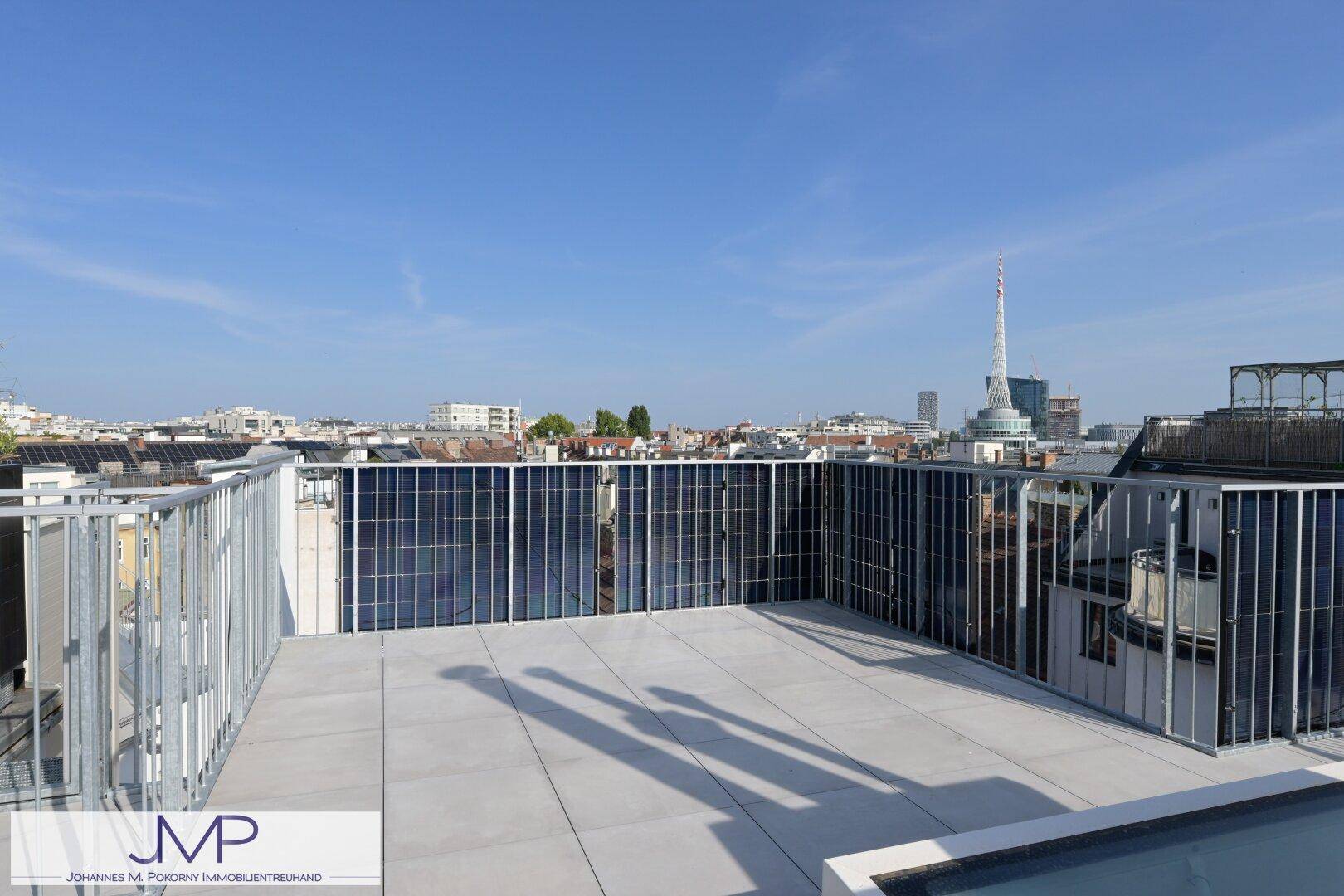 Dachterrasse mit Fliesenboden, Brüstung und integrierten Solarpaneelen.