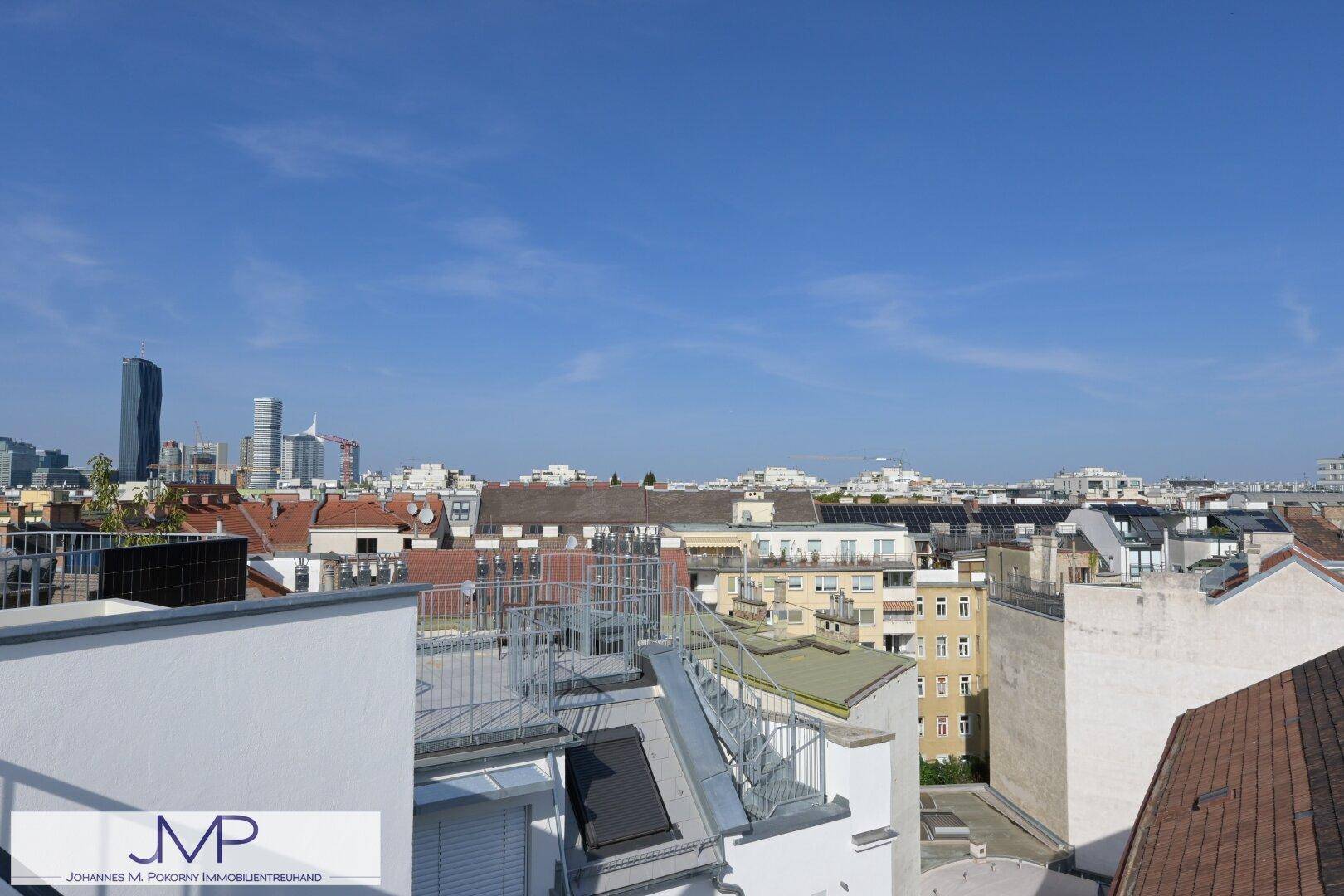 Dachterrasse mit weitem Blick auf die Stadt und moderne Hochhäuser am Horizont.
