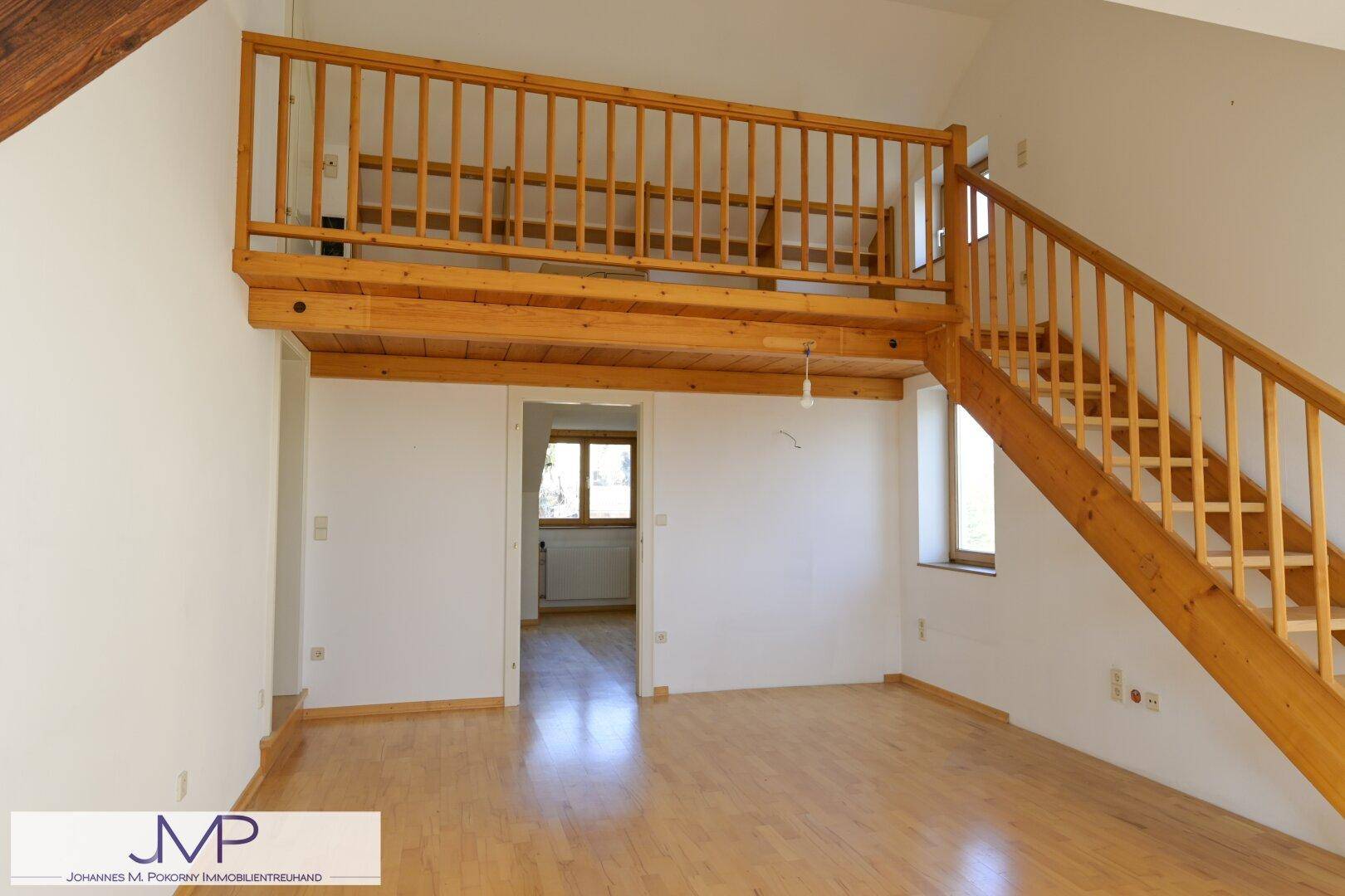 Helles Dachzimmer mit Holztreppe, Galerie und Parkettboden.