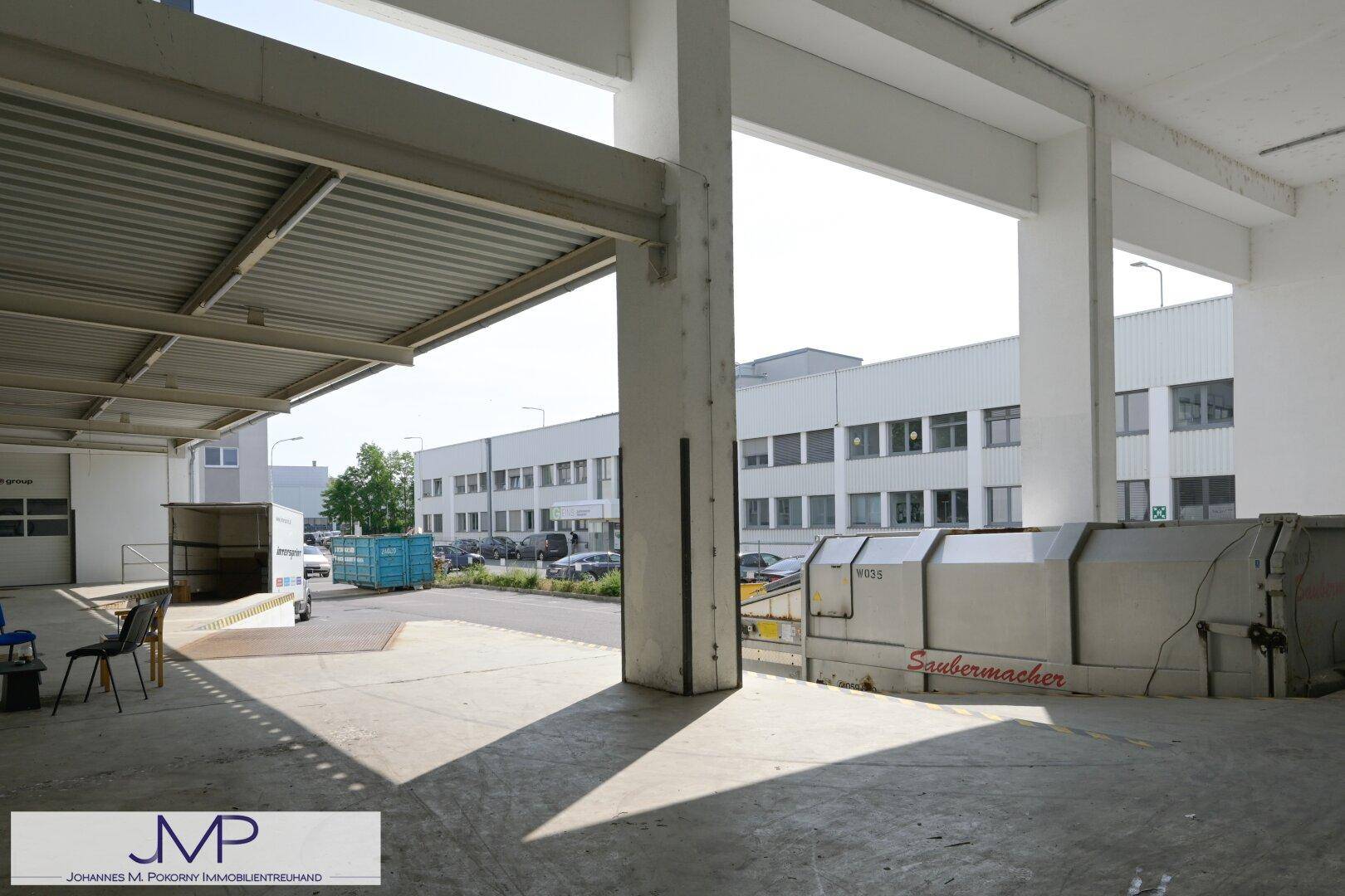 Überdachte Laderampe mit Säulen und Containern im Hintergrund, ideal für Logistik.