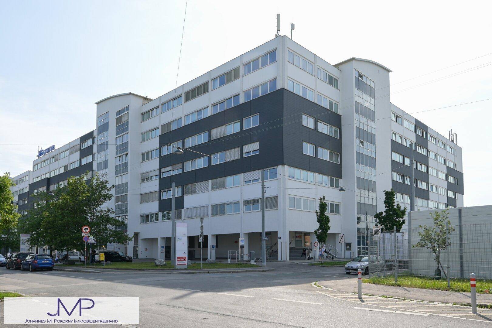 Modernes Bürogebäude mit weißer und dunkler Fassade, großen Fenstern und einer Straßenecke.