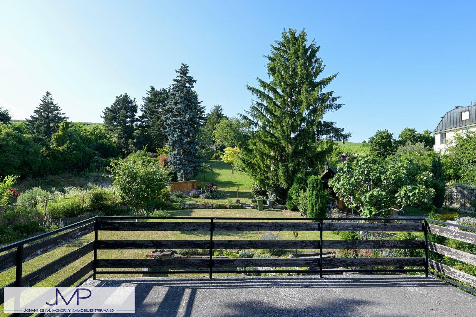 Große Terrasse mit Holzgeländer und weitem Blick über den grünen, gepflegten Garten.