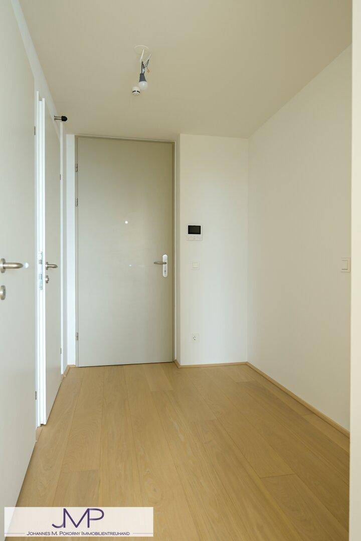 Heller Flur mit Holzboden und mehreren weißen Türen, die zu den Zimmern führen.