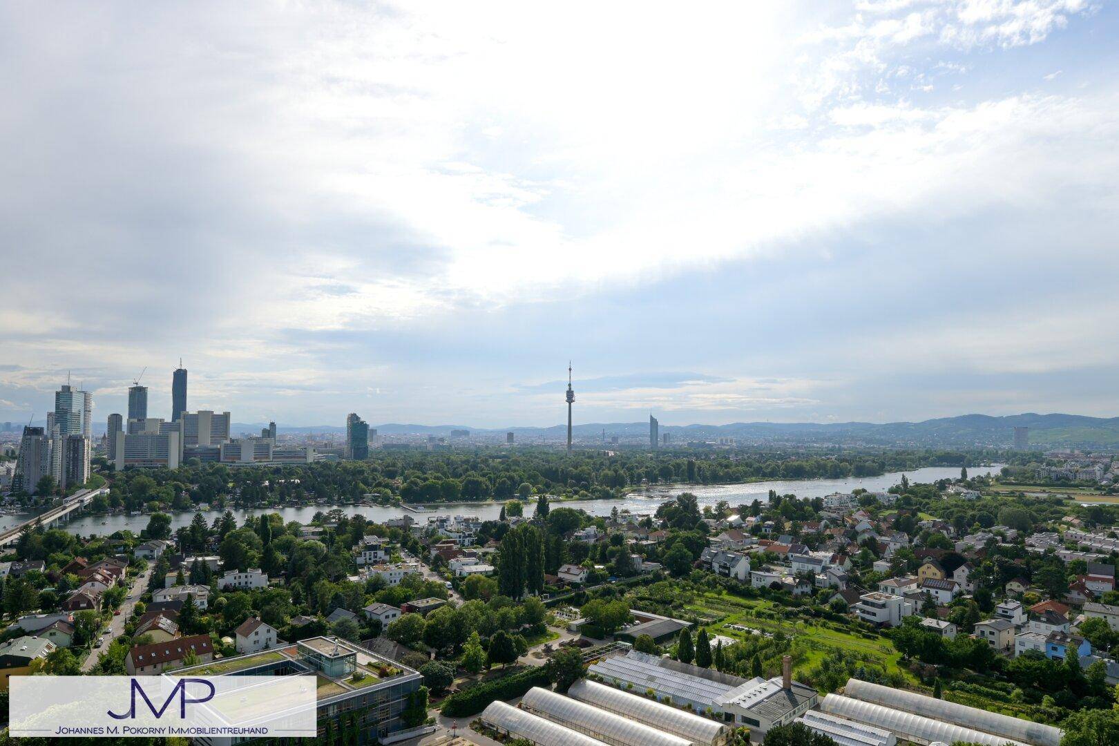 Ausblick über die Stadt mit Fluss, Hochhäusern und dem markanten Donauturm am Horizont.