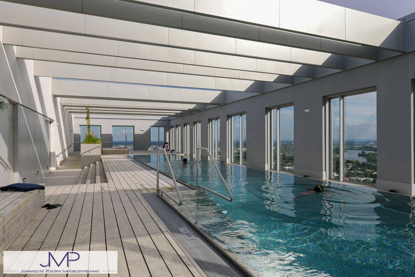 Moderner Innenpool mit Holzdeck und weitem Blick auf die umliegende Stadtlandschaft.