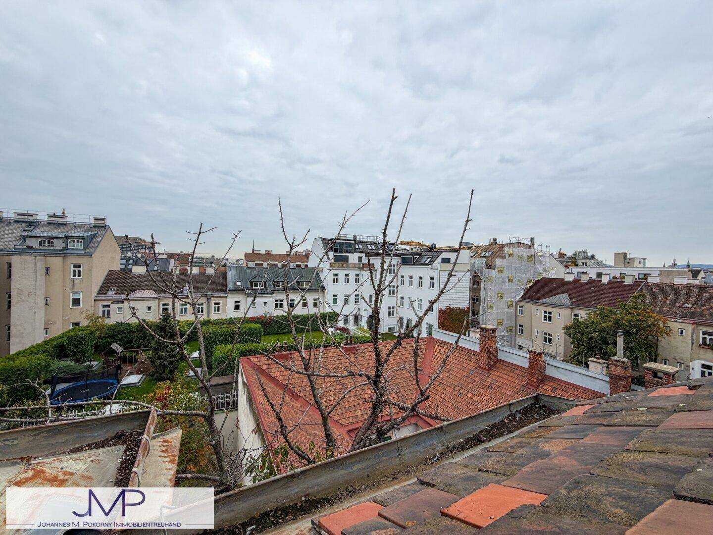 Weitläufiger Blick über die Dächer der Stadt, Gärten und umliegende Gebäude.