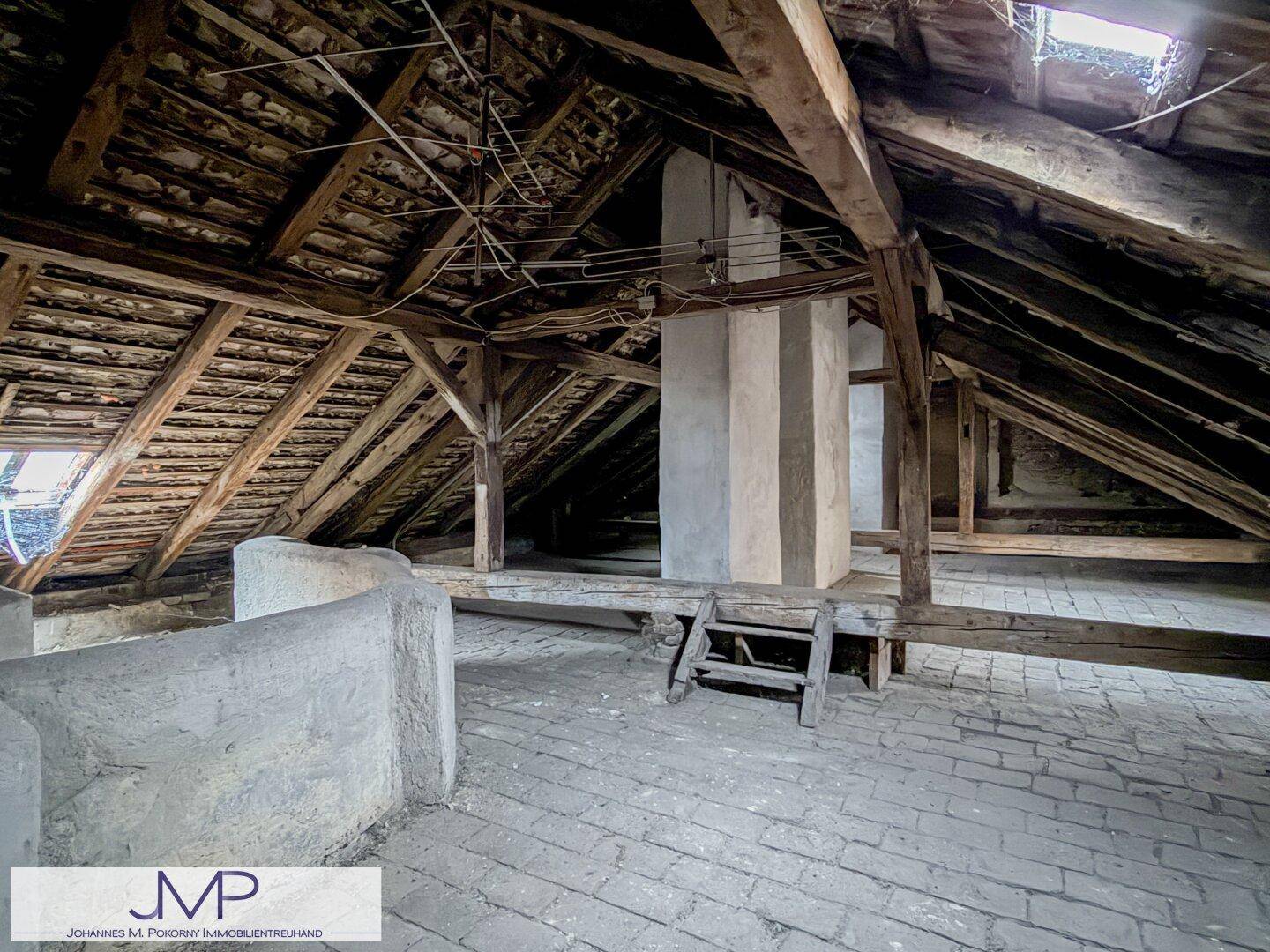 Geräumiger Dachboden mit sichtbaren Holzbalken, Ziegelboden und viel Potenzial für Ausbau.