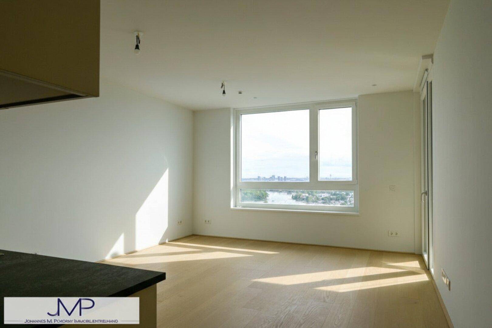 Helles Wohnzimmer mit Holzboden und weitem Blick auf die Stadt und das Wasser.