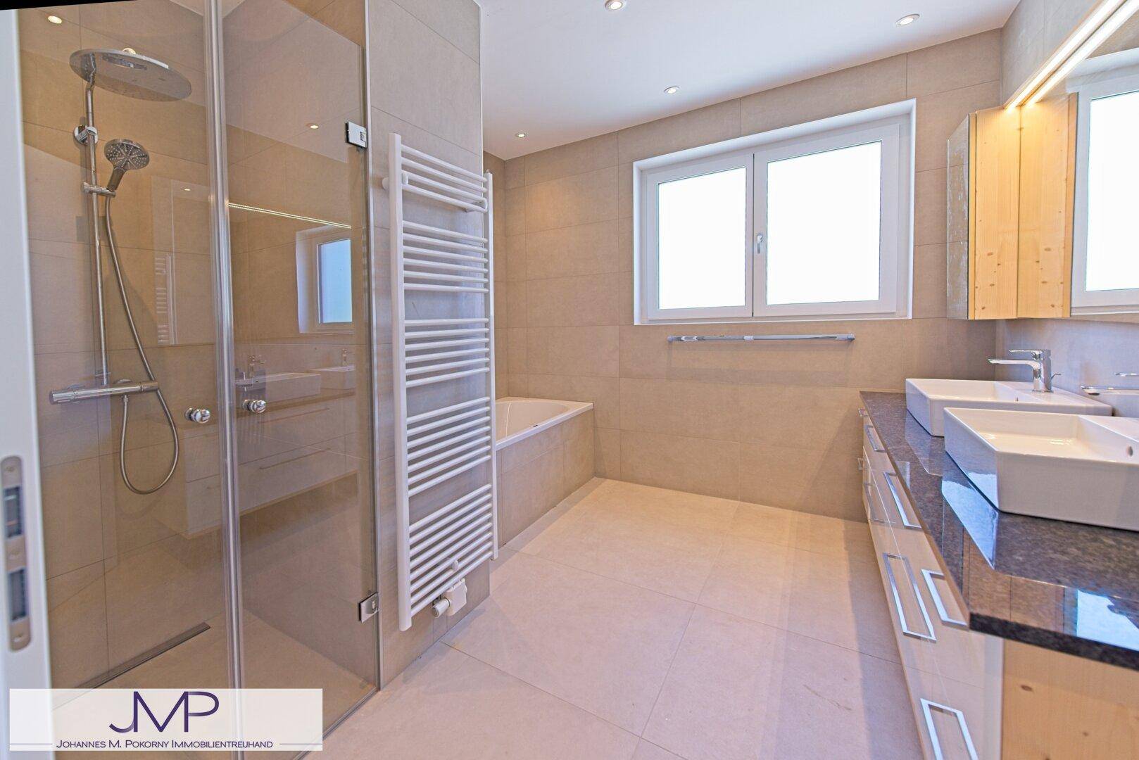 Modernes Badezimmer mit beigen Fliesen, Doppelwaschbecken, begehbarer Dusche und Badewanne.