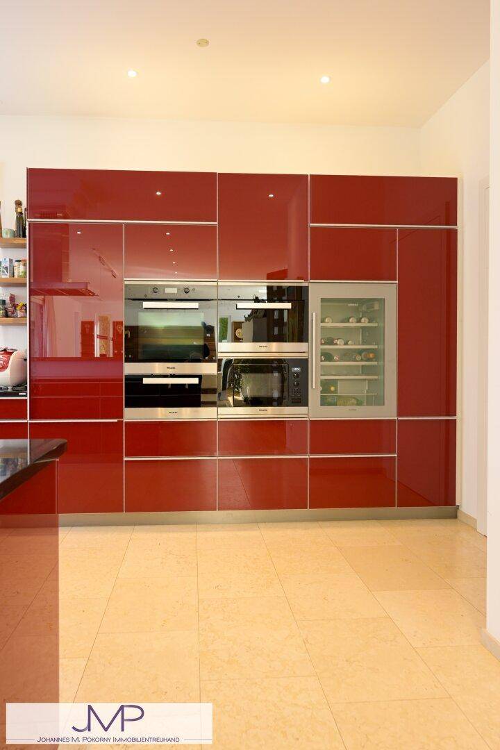 Integrierte Küchenzeile mit roten Hochglanzschränken und modernen Einbaugeräten, inklusive Weinkühler.
