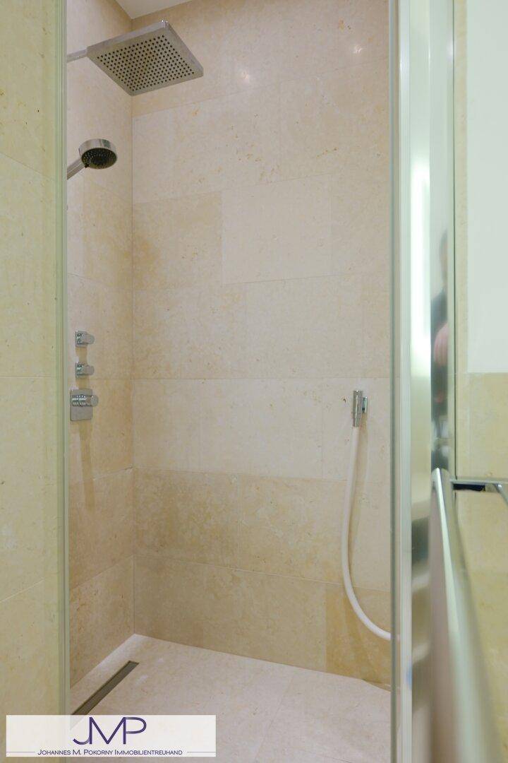 Moderne begehbare Dusche mit Regenduschkopf und hellen Fliesen, sehr geräumig.