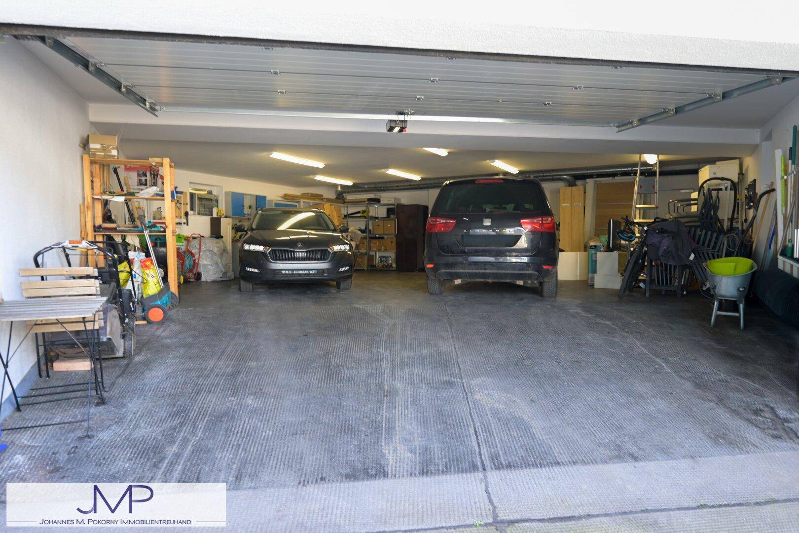 Geräumige Garage mit Platz für zwei Fahrzeuge und zusätzlichem Stauraum für diverse Gegenstände.