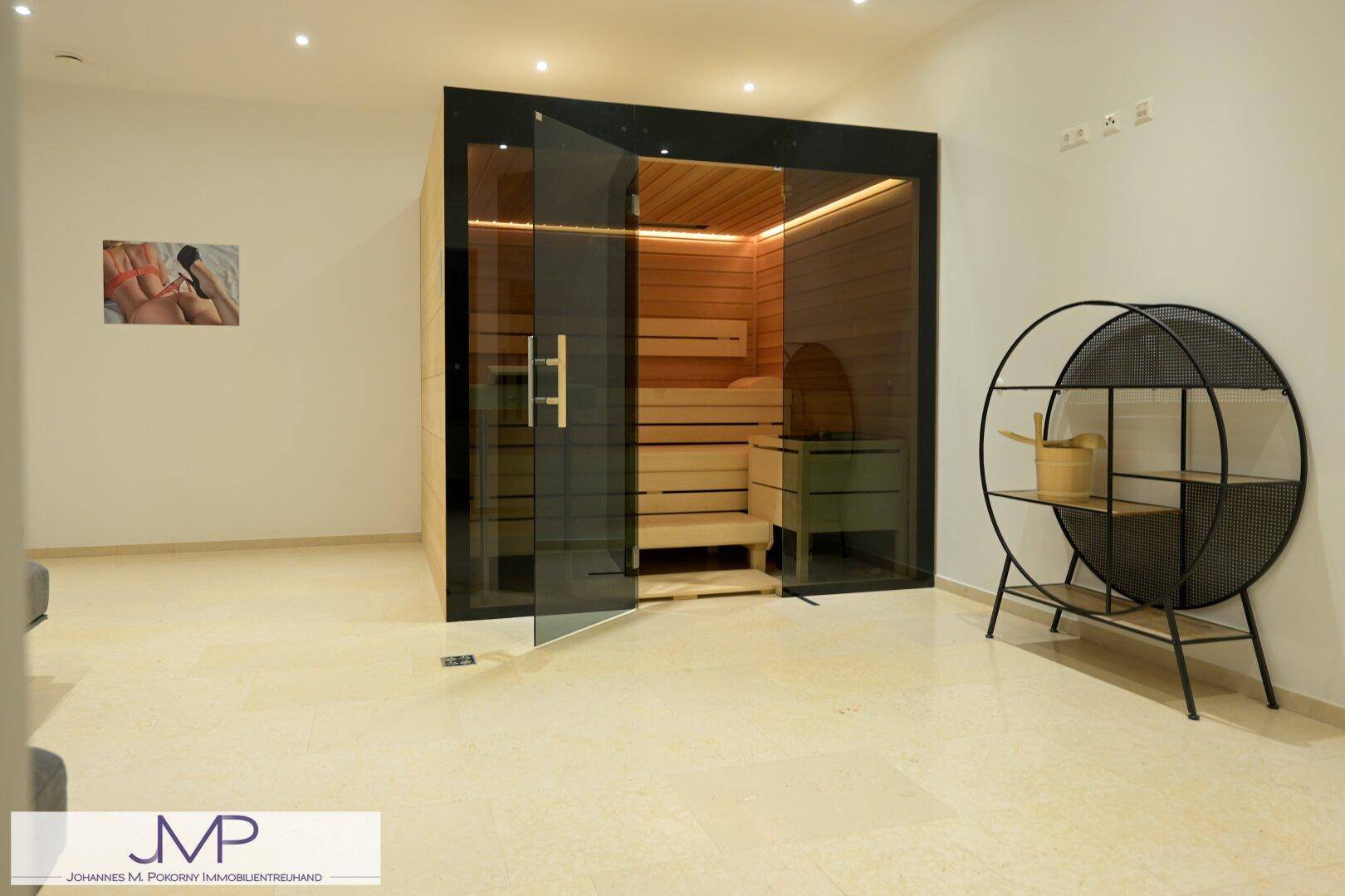 Moderne Sauna mit Glasfront und Holzbänken, Teil eines privaten Wellnessbereichs.