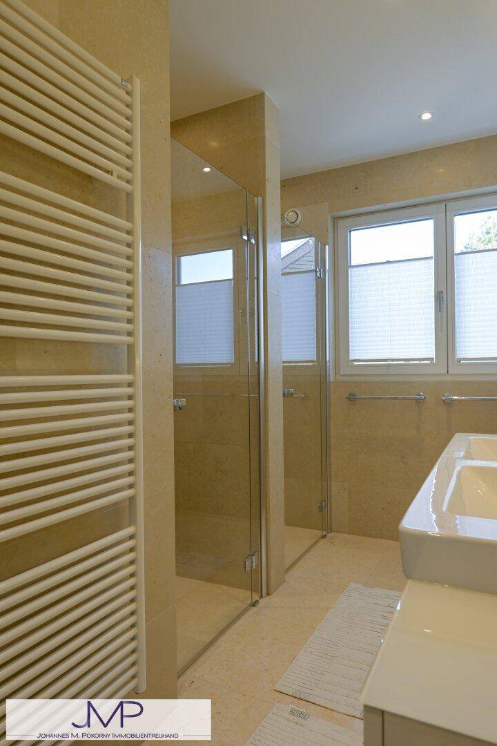 Modernes Badezimmer mit beigen Fliesen, begehbarer Dusche und beheiztem Handtuchhalter.
