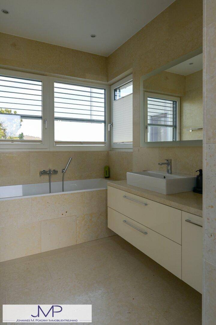 Modernes Badezimmer mit beiger Verkleidung, integrierter Badewanne und schwebendem Waschtisch.