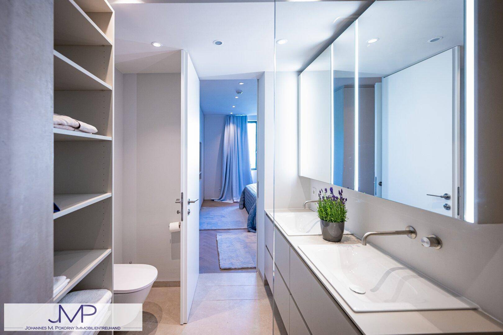 Modernes Badezimmer mit Doppelwaschbecken, Spiegelschrank und direktem Zugang zum Schlafzimmer.