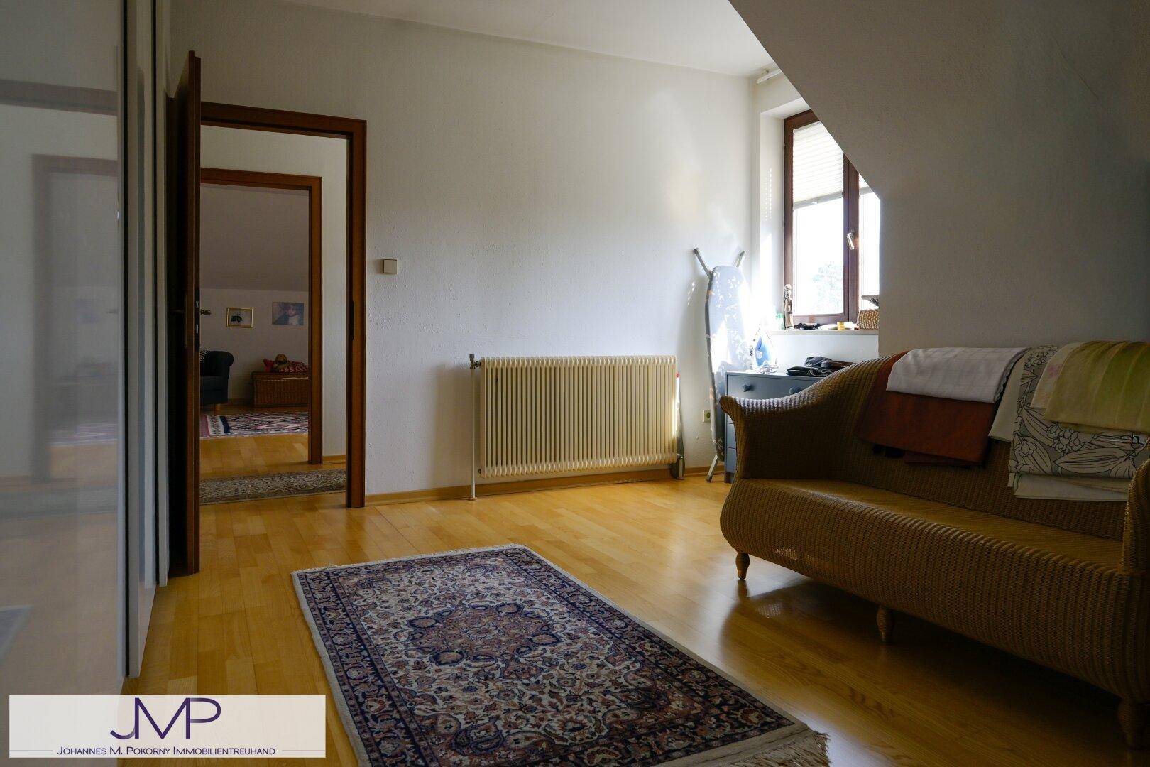 Geräumiges Dachzimmer mit Holzboden und einem bequemen Sofa, das vielseitig genutzt werden kann.