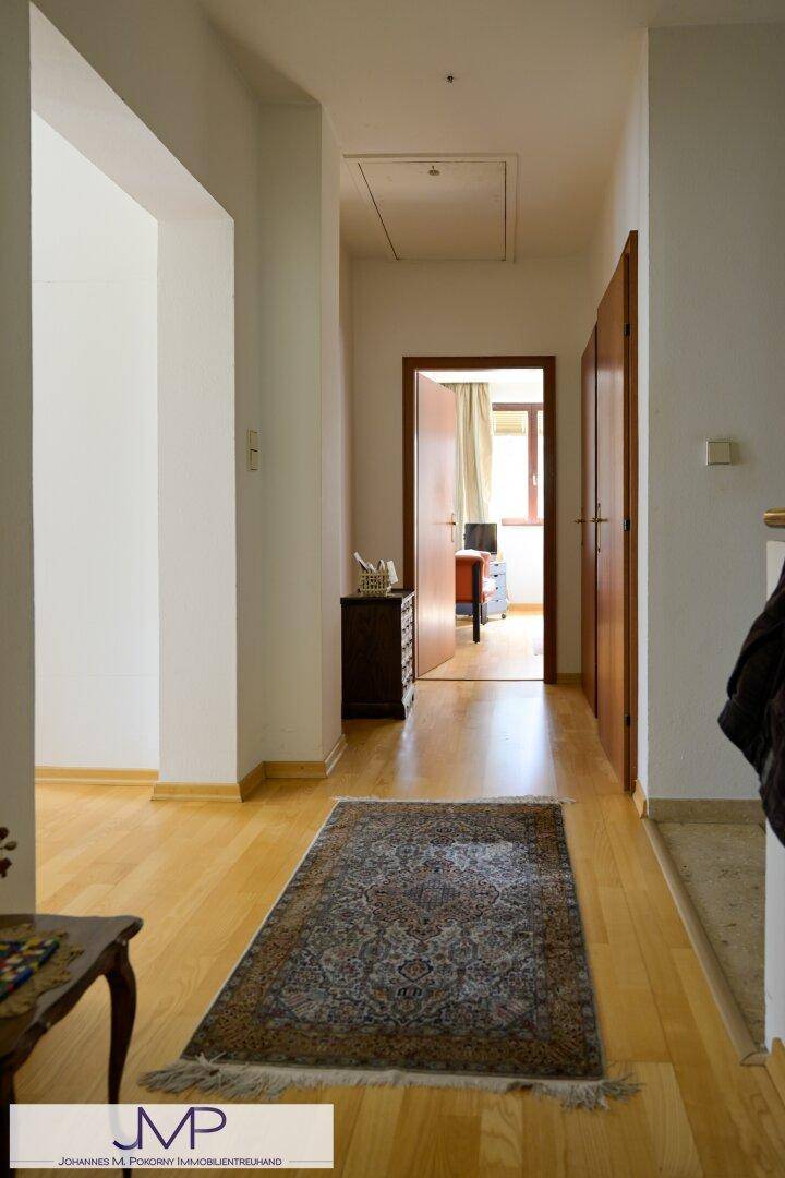 Heller Flur mit Holzboden und einem Teppich, der zu den angrenzenden Räumen führt.