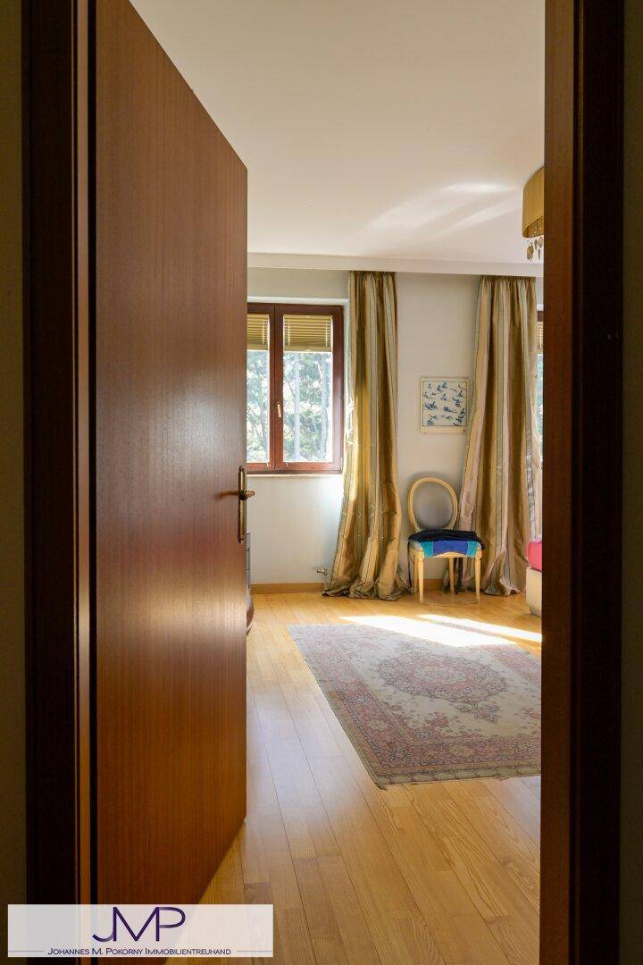 Einladendes Schlafzimmer mit Holzboden und großen Fenstern, die viel Tageslicht hereinlassen.