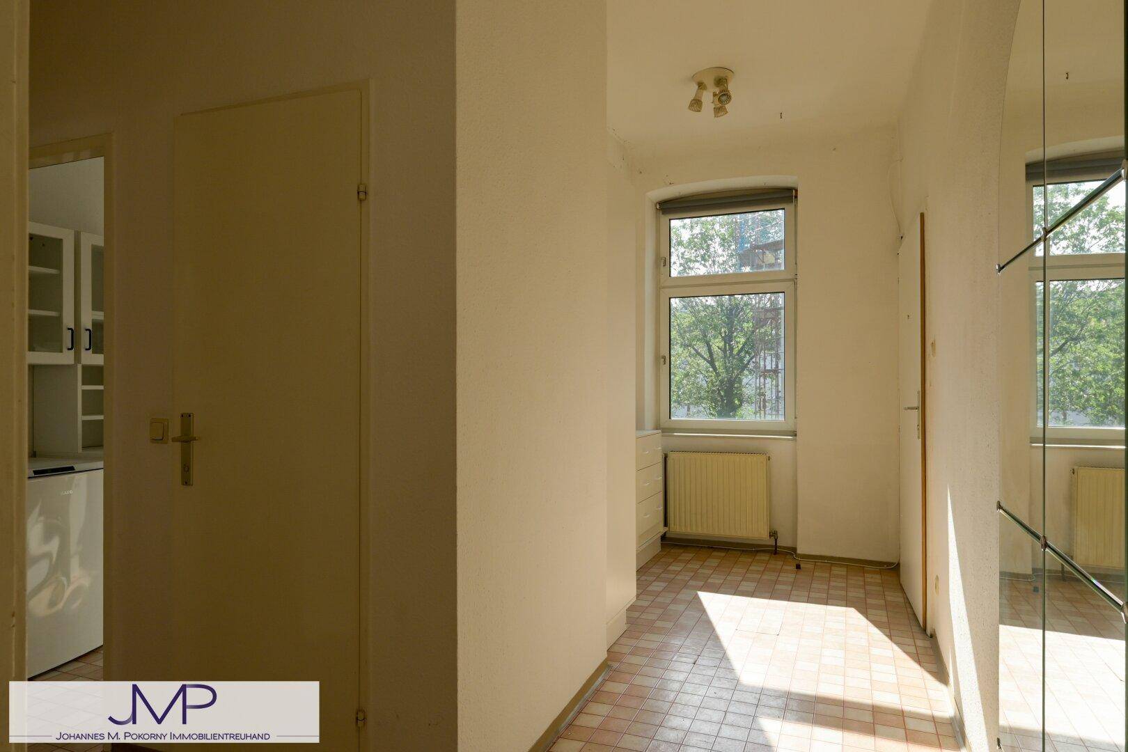 Heller Flur mit Fliesenboden, Fenster und Spiegelschrank, bietet praktischen Stauraum.