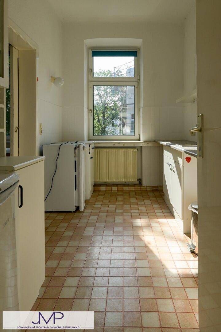 Kleine Küche mit Fliesenboden, Fenster und einfacher Küchenzeile, hell und funktional.