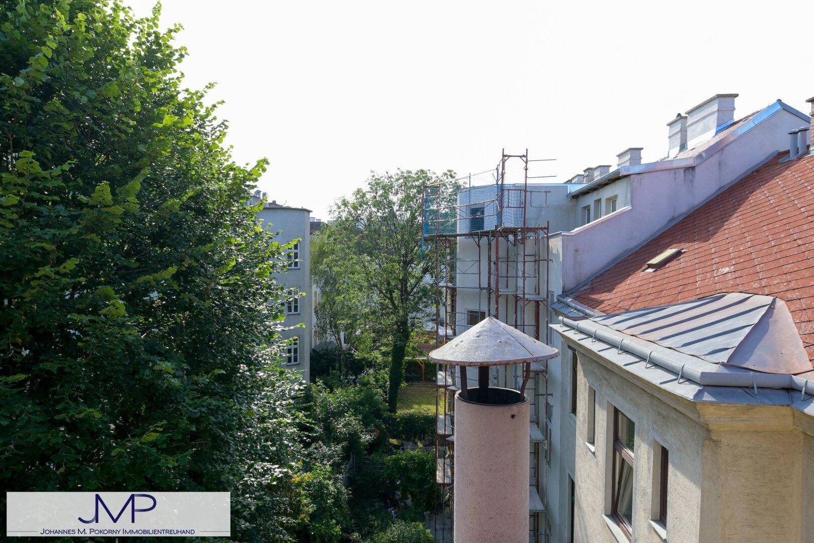 Ausblick auf umliegende Gebäude, Bäume und ein Gerüst an einem Nachbargebäude.