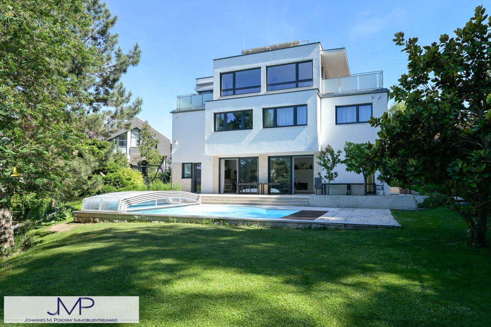 Moderne Villa mit großem Garten und Poolbereich, umgeben von üppiger Vegetation.