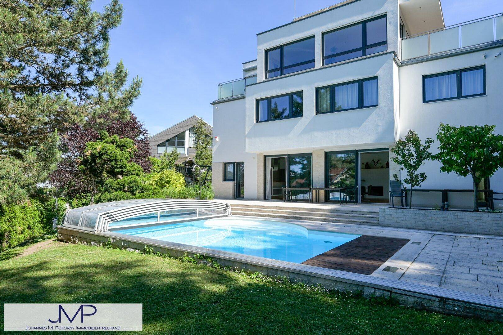 Moderne Villa mit großzügiger Terrasse und Poolbereich, umgeben von einem grünen Garten.