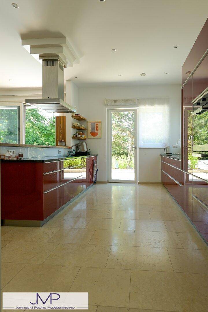 Moderne Küche mit roten Hochglanzfronten und Zugang zum Garten, hell und funktional.
