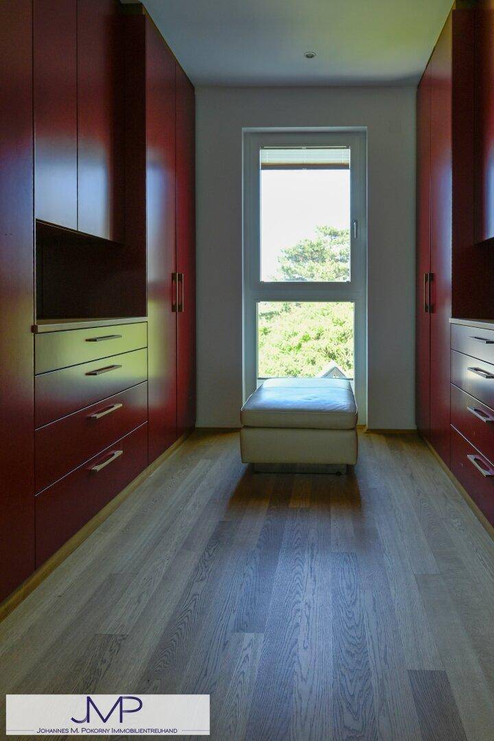 Geräumiger begehbarer Kleiderschrank mit roten Einbauschränken und Fenster für Tageslicht.