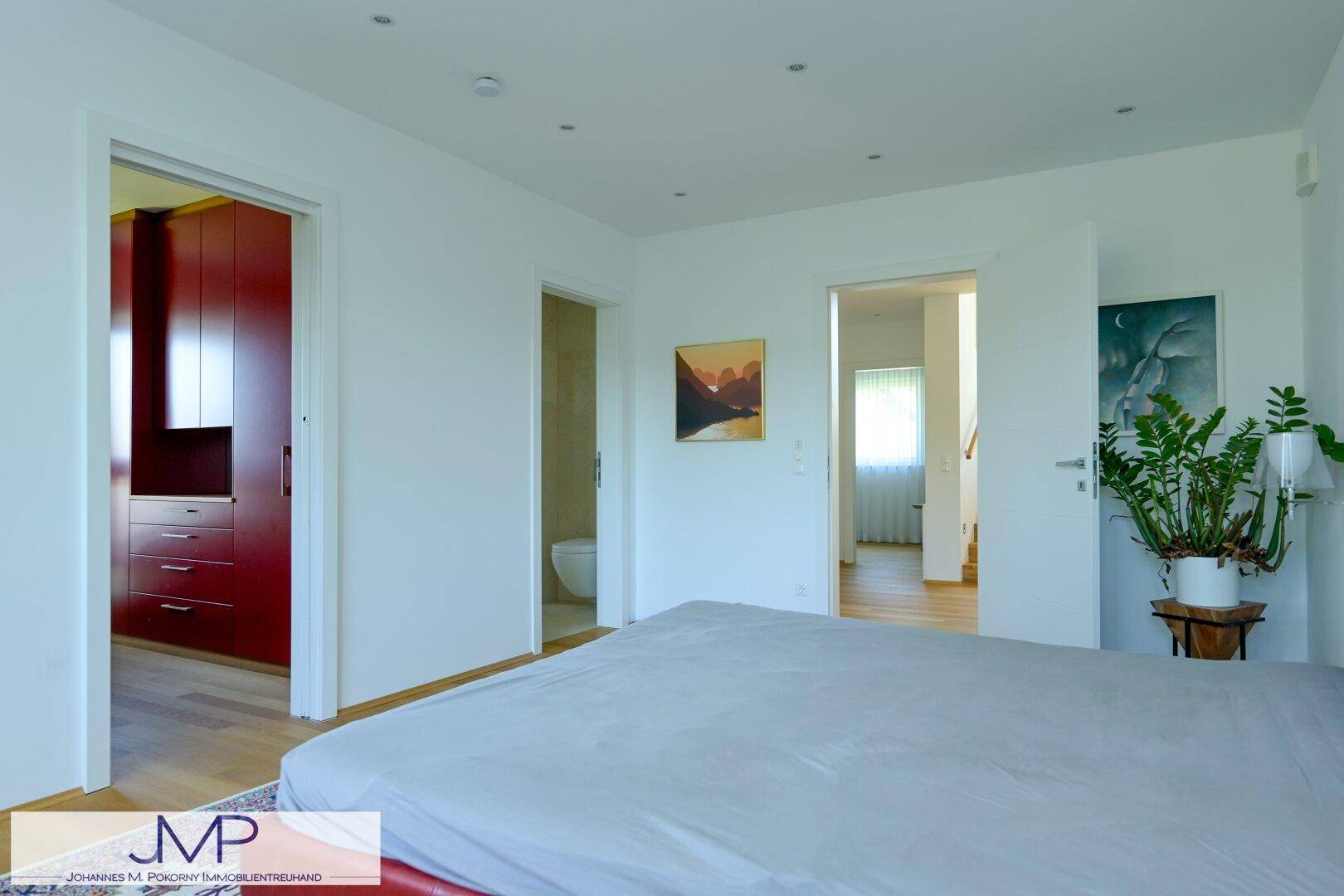 Schlafzimmer mit rotem Bett und Zugang zu einem begehbaren Kleiderschrank sowie einem Badezimmer.