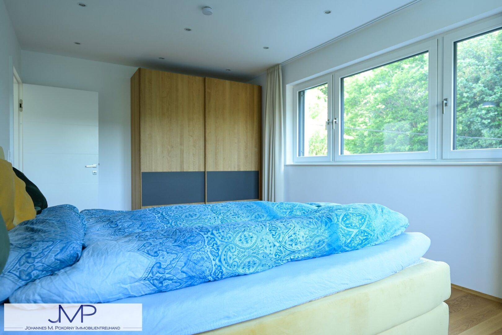 Schlafzimmer mit gelbem Bett, modernem Holzschrank und großen Fenstern für viel Tageslicht.