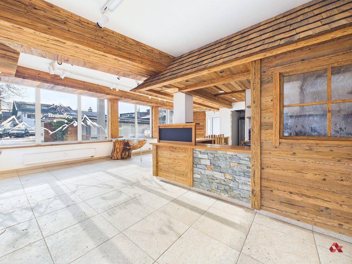 Rustikaler Innenbereich mit viel Holz, Steinverkleidung an der Theke und großen Fenstern für viel Helligkeit.