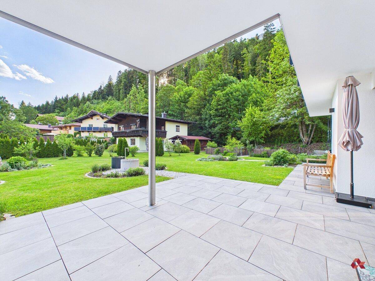 Überdachte Terrasse mit Blick auf den weitläufigen Garten und die umliegende Natur.