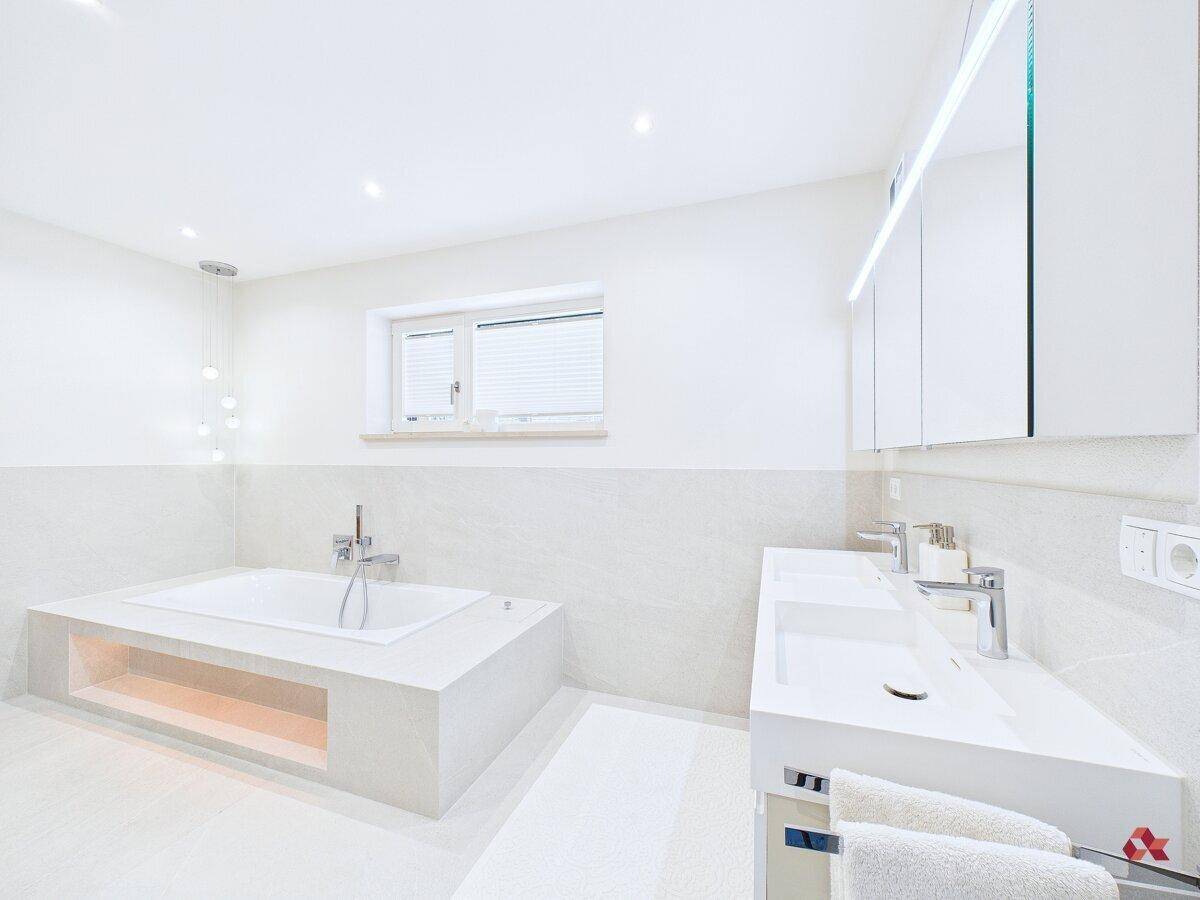 Großes Badezimmer mit Doppelwaschbecken, Badewanne und Spiegelschrank.