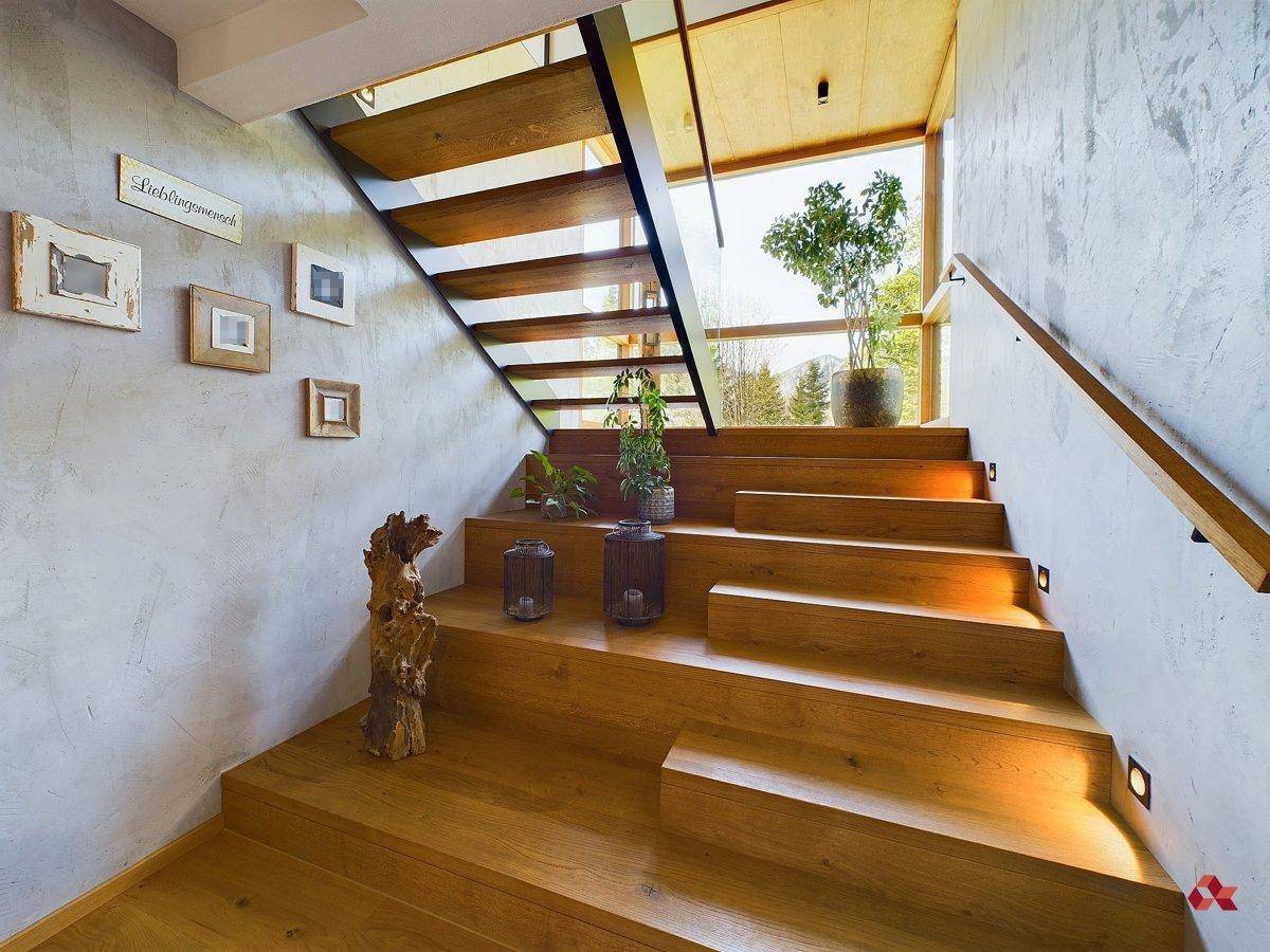 Elegante Holztreppe mit großen Fenstern, die einen schönen Blick ins Grüne bieten und viel Licht hereinlassen.