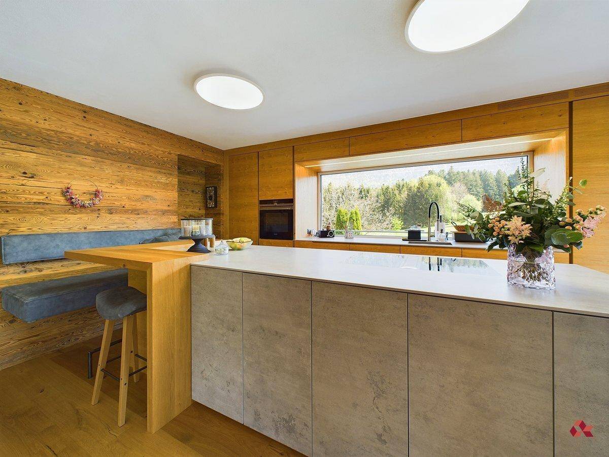 Geräumige Küche mit Holzschränken, großer Fensterfront und integrierter Frühstücksbar mit Sitzgelegenheiten.