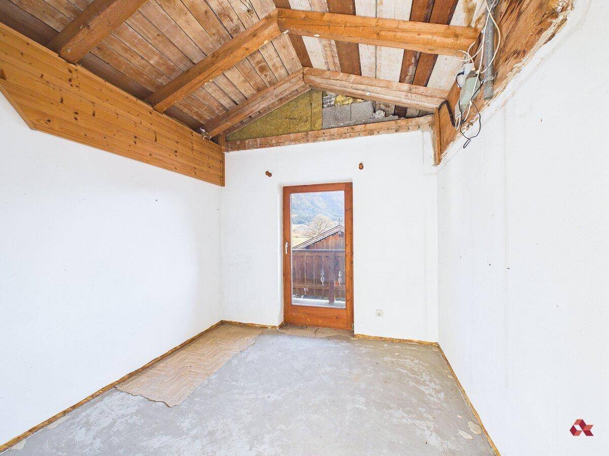 Dachbodenraum mit Holzbalken, Dachschräge und Zugang zu einem Balkon.