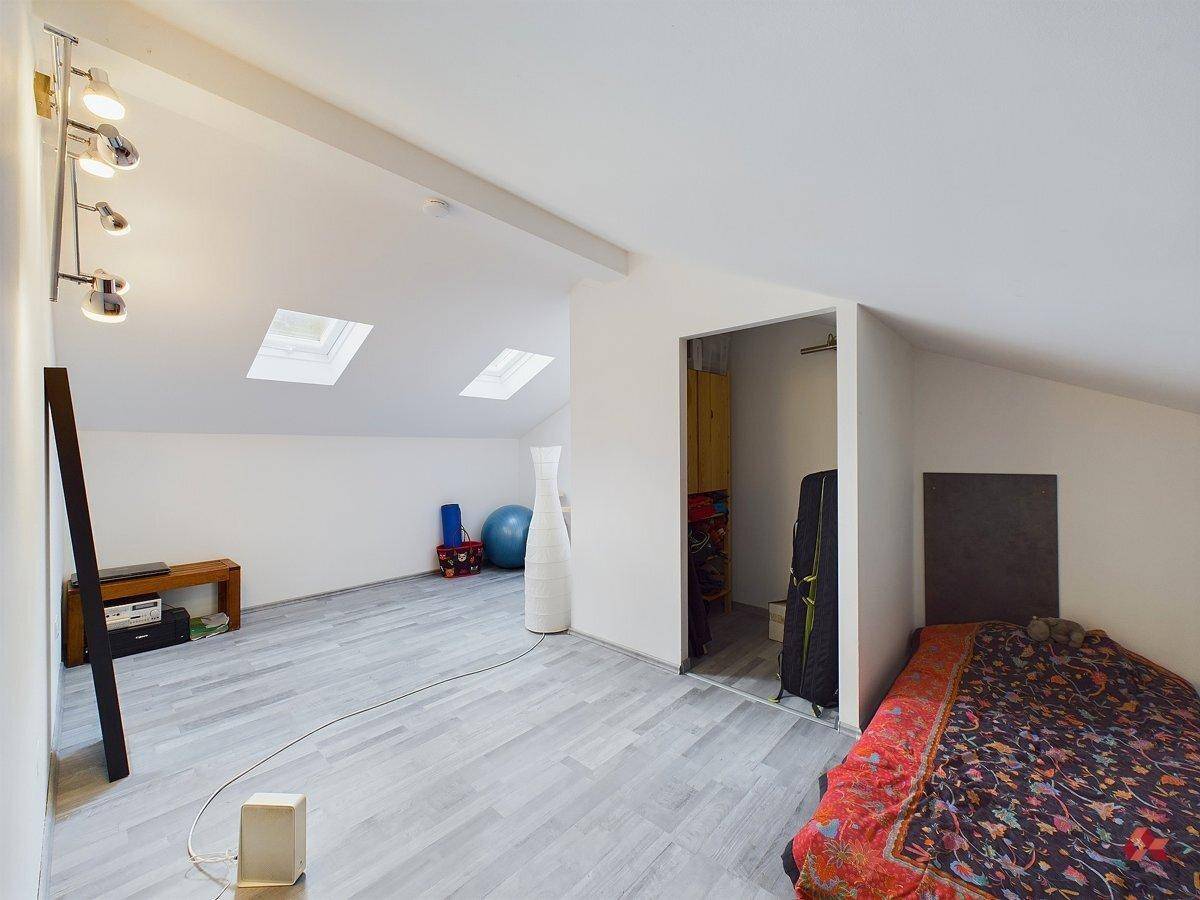 Dachgeschosszimmer mit schrägen Wänden, Dachfenstern und hellem Laminatboden, ideal als Schlafbereich.