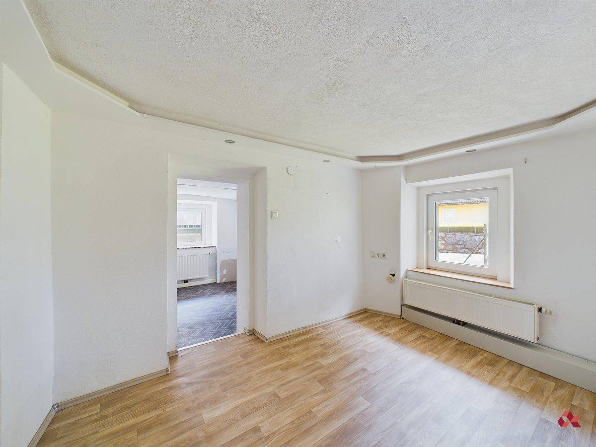 Leerer Raum mit Laminatboden und Fenster, bietet Potenzial für individuelle Gestaltung.