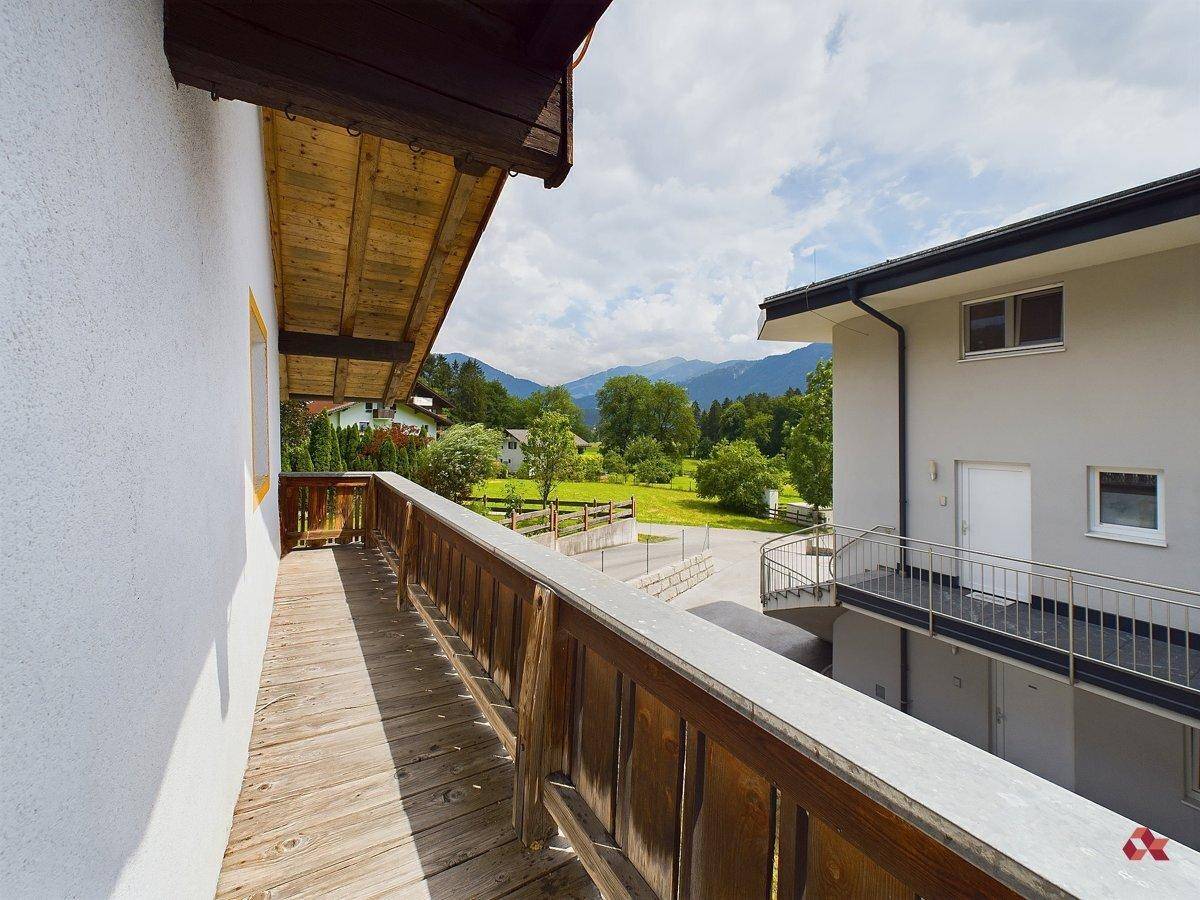 Langer Holzbalkon mit Bergblick und Blick auf die grüne Umgebung.