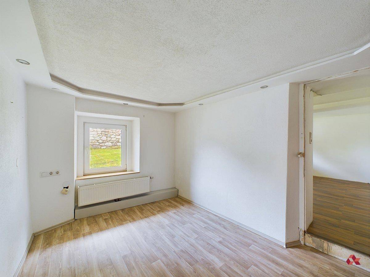 Heller, leerer Raum mit Laminatboden und einem Fenster, bereit für die Einrichtung.